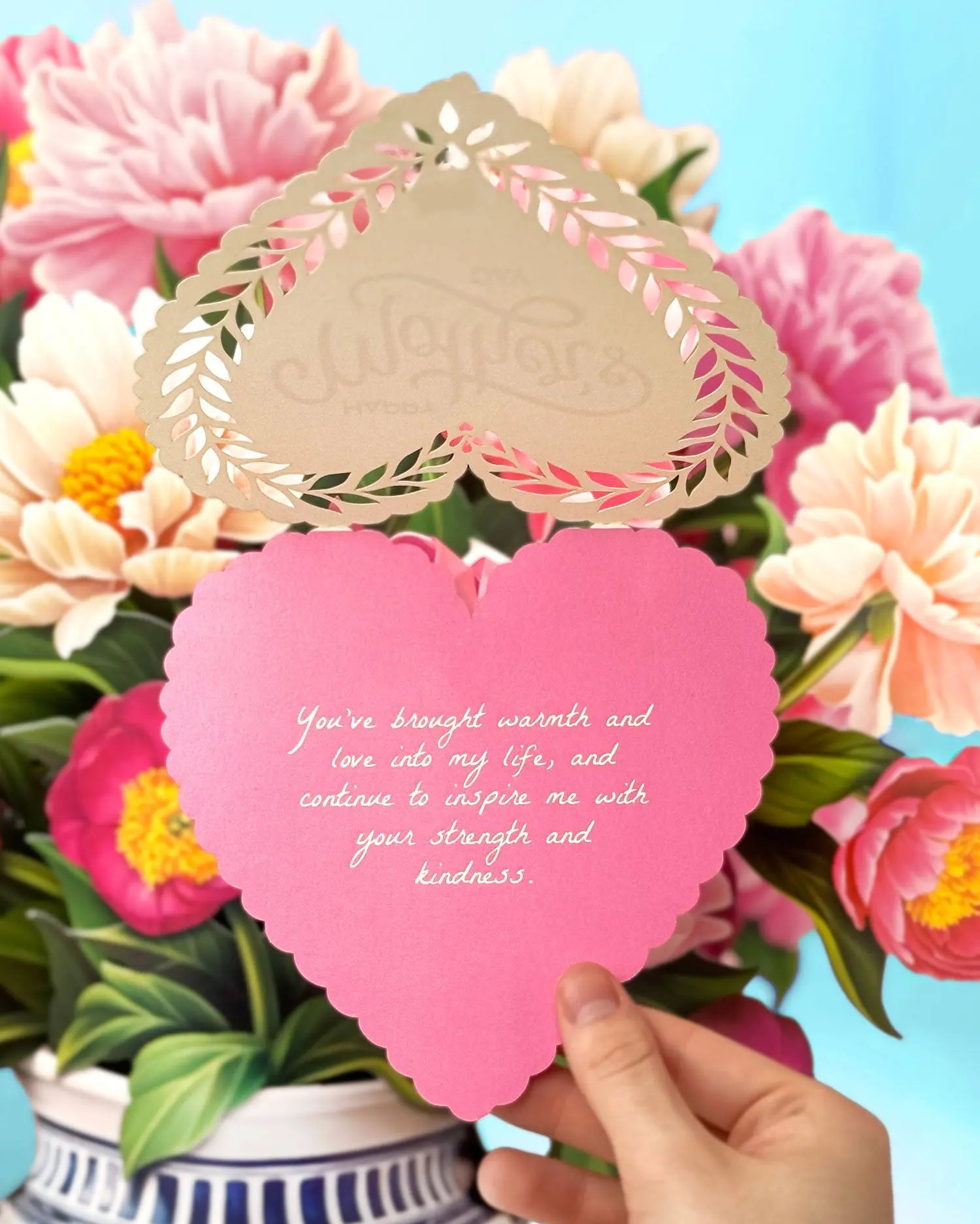 a hand holding a pink heart shaped card