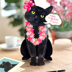 FreshCut Paper Black cat pop-up card with pink flowers and a speech bubble on a wooden surface.