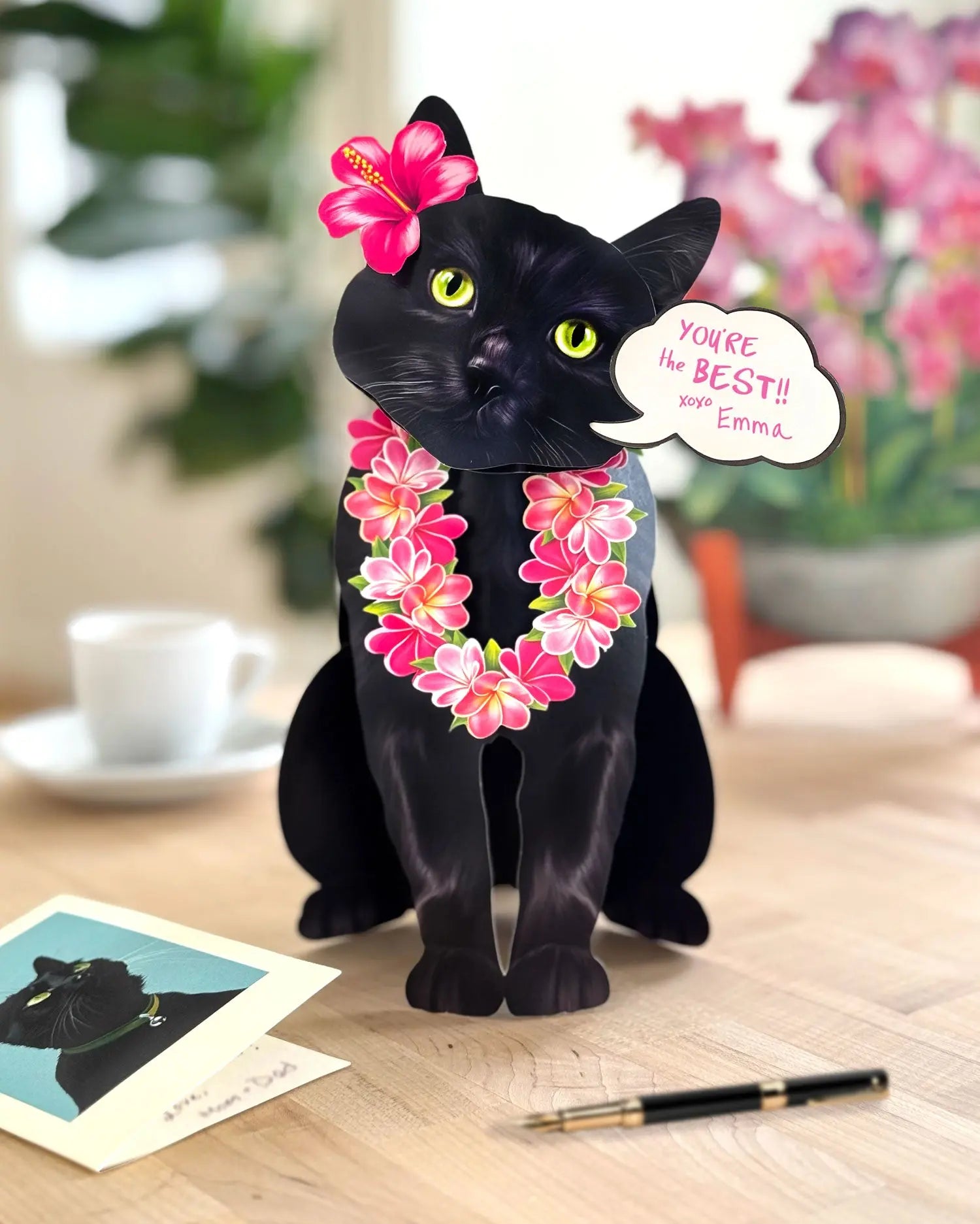 FreshCut Paper Black cat pop-up card with pink flowers and a speech bubble on a wooden surface.