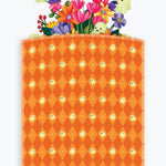 A Halloween-themed branded envelope bag packaging with an orange and yellow argyle pattern featuring small ghost motifs, with a colorful floral pop-up peeking out and a purple banner reading 'Happy Halloween!'.