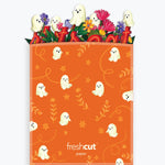 An orange Halloween-themed branded envelope with a ghost pattern, shown filled with colorful paper pop-art ghosts and flowers against a light gray background.