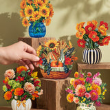 A hand holds a small woven basket filled with autumn flowers and decorative stems, surrounded by several other floral arrangements in colorful vases and pots on wooden blocks against a warm sage green wall.