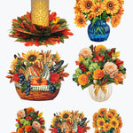 A set of autumn-themed decorative illustrations on a white background, including a glowing pillar candle in a floral base, sunflower bouquets in blue and white vases, a fall harvest basket with pumpkins, grapes, and wheat, and smaller floral arrangements. A small orange circle at bottom left reads '2X EACH'.