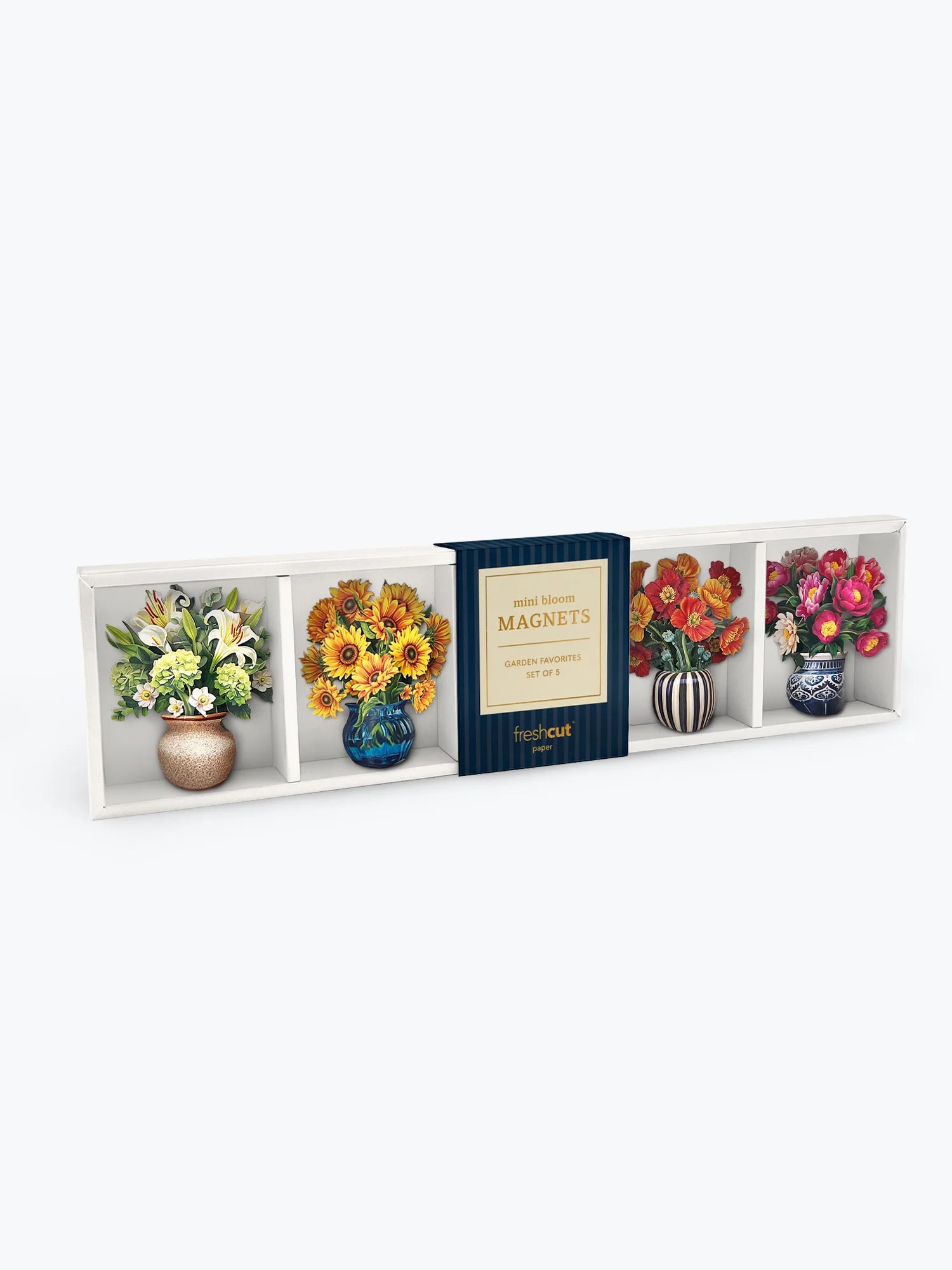 A boxed floral magnet set displayed against a light gray background. The package contains four decorative magnets shaped like vases with flowers, including white lilies, yellow sunflowers, red roses, and pink peonies, with a dark blue center label reading 'Mini Bloom Magnets'.