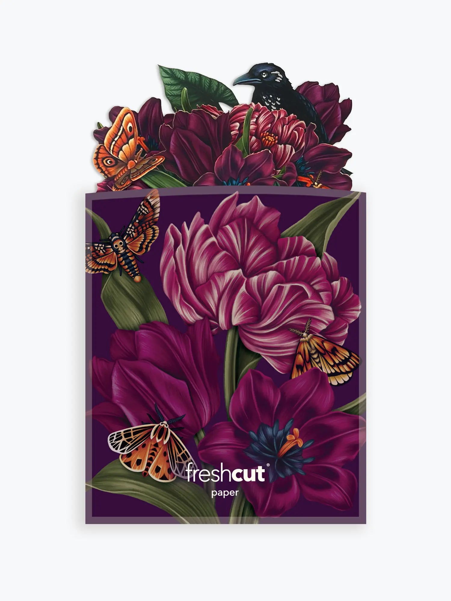 A branded envelope featuring a dark purple background with large magenta flowers, green leaves, orange butterflies, and a black bird perched at the top. The words 'freshcut paper' are printed near the bottom.