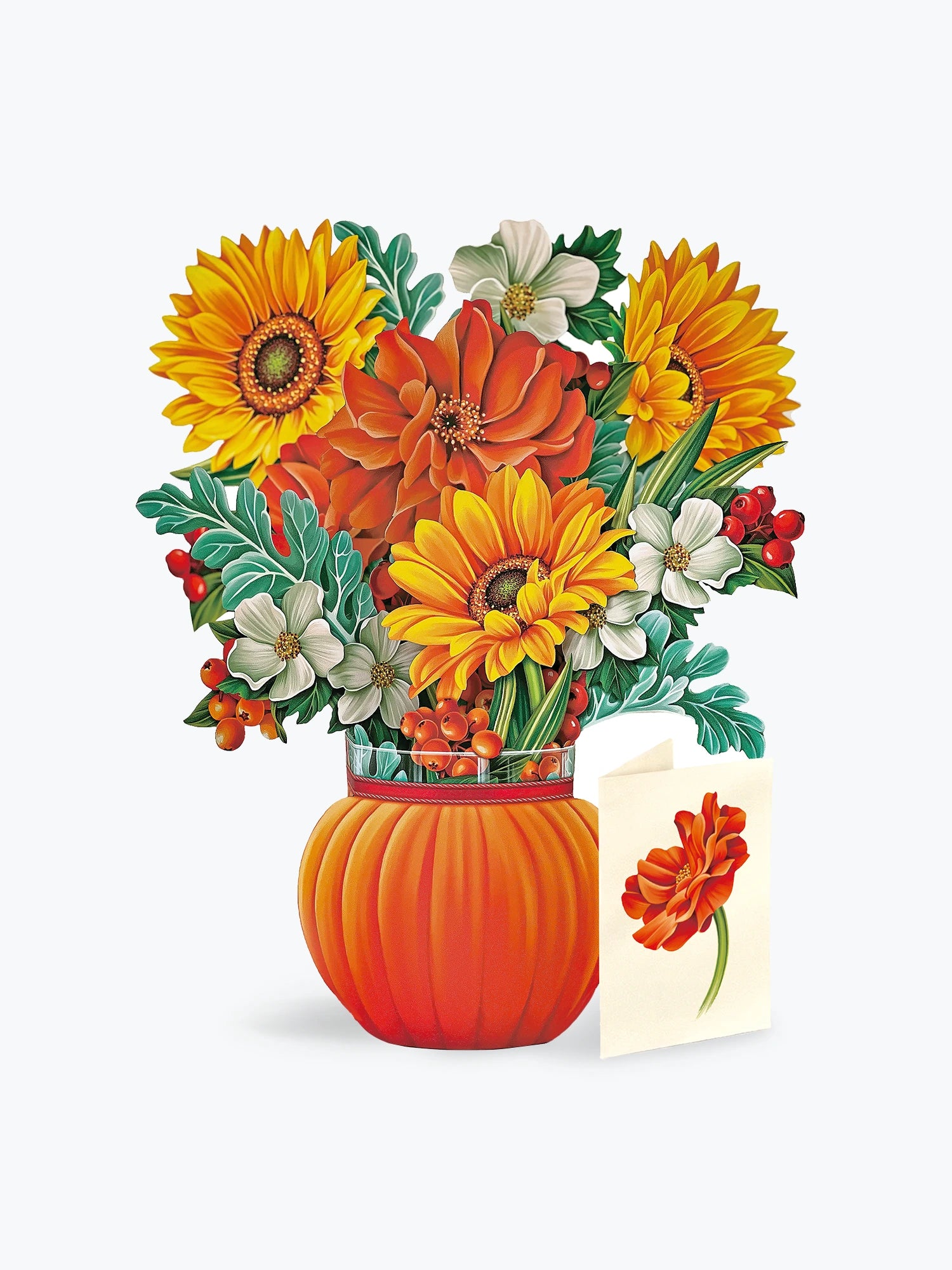 A floral paper pop-up arrangement in a ribbed orange pumpkin-shaped vase, featuring yellow and orange flowers with green leaves and small red berries, alongside a small card with a matching flower illustration, on a light gray background.
