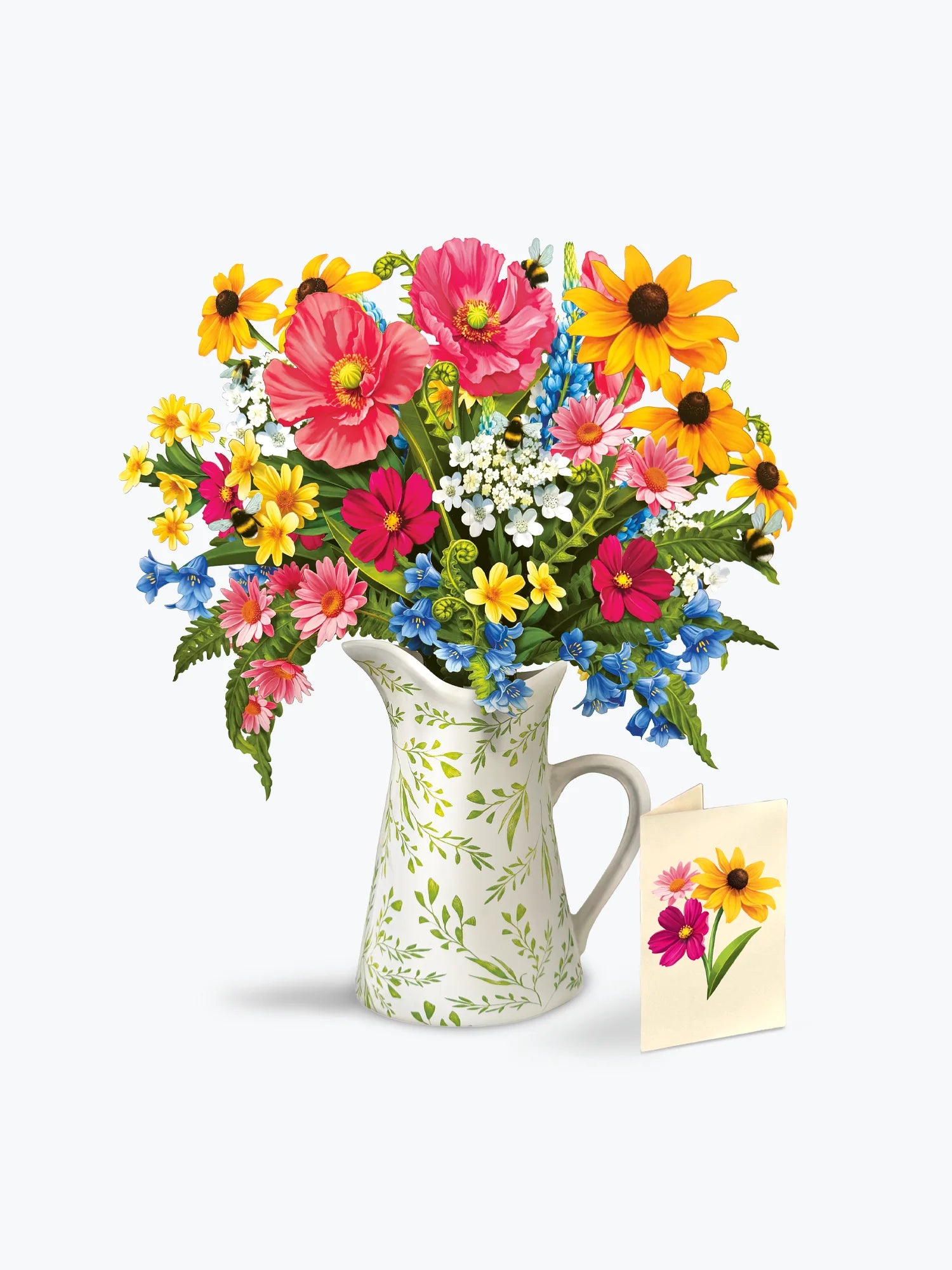 A vibrant mixed flower bouquet in a white ceramic pitcher with a green leaf pattern, accompanied by a small matching flower card on a clean white background.