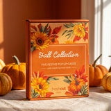 A boxed card set labeled 'Fall Collection' stands on a tablecloth in a styled autumn scene with pumpkins and warm sunlight. The box has orange, yellow, and red floral artwork and visible 'freshcut paper' logo branding.