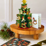 Mini Christmas Tree pop-up decoration displayed on a table with its matching holiday notecard and ornament sheet.